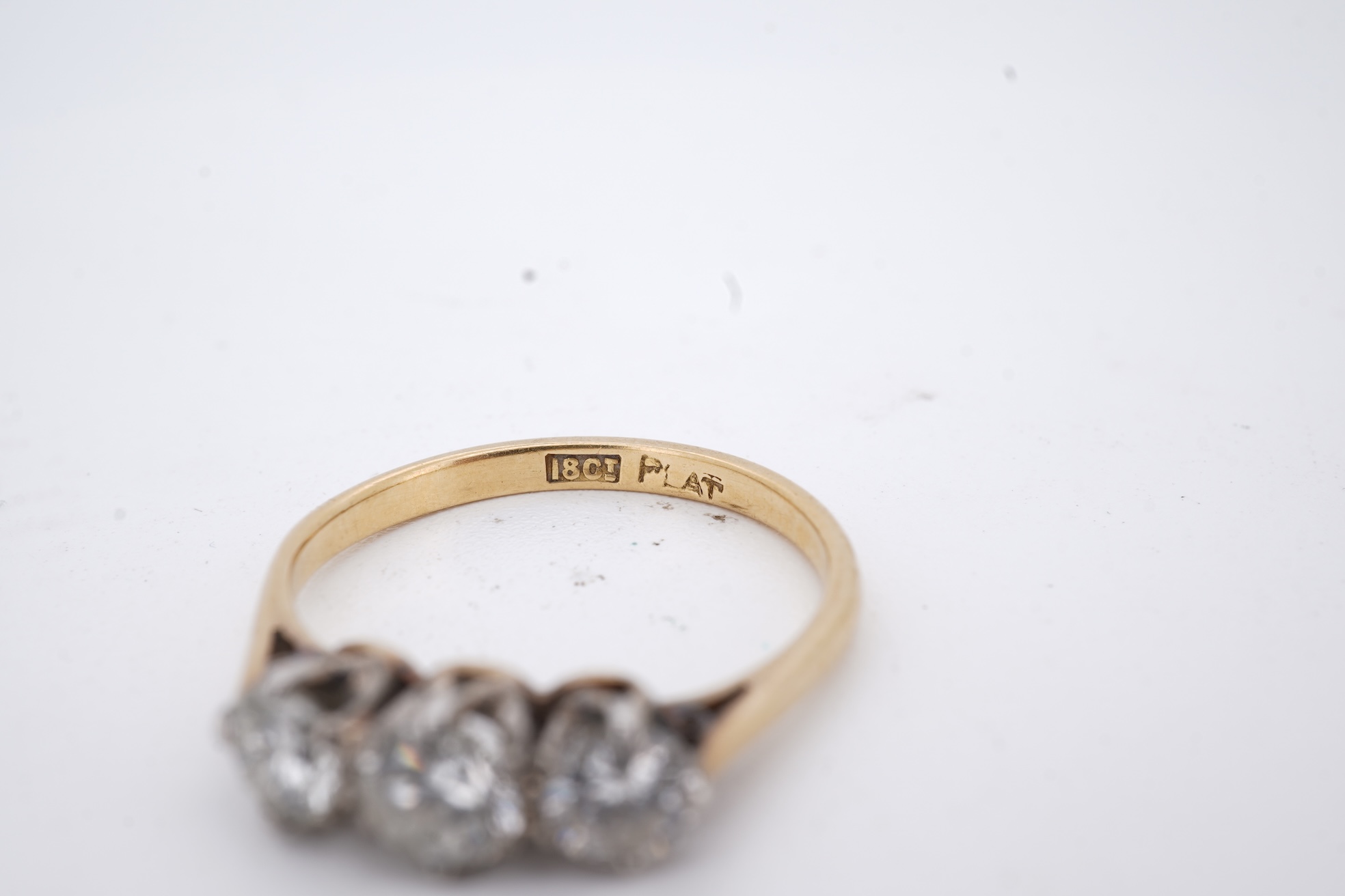 A yellow metal (stamped 18ct, & plat) and three stone diamond set ring, size L, gross weight 2.1 grams.